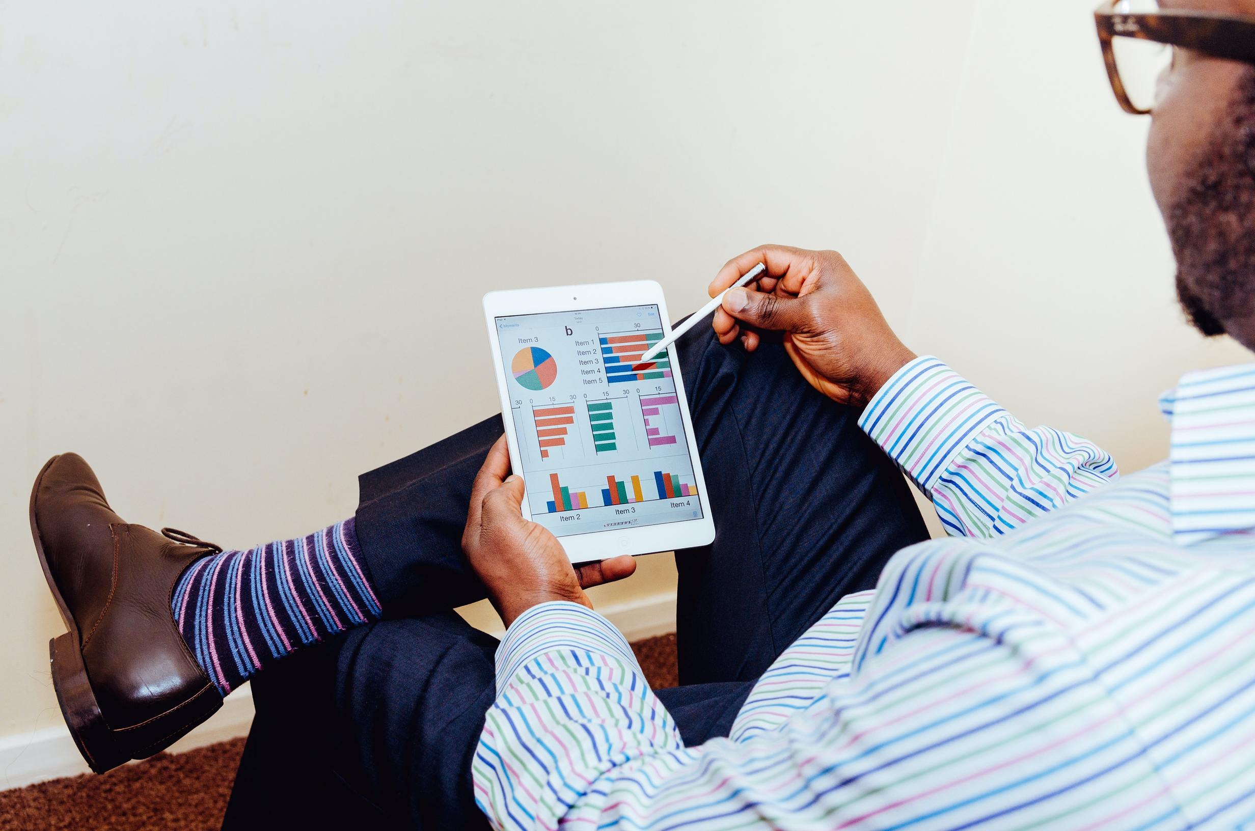 A man sitting and watching on tablet with product sales charts.