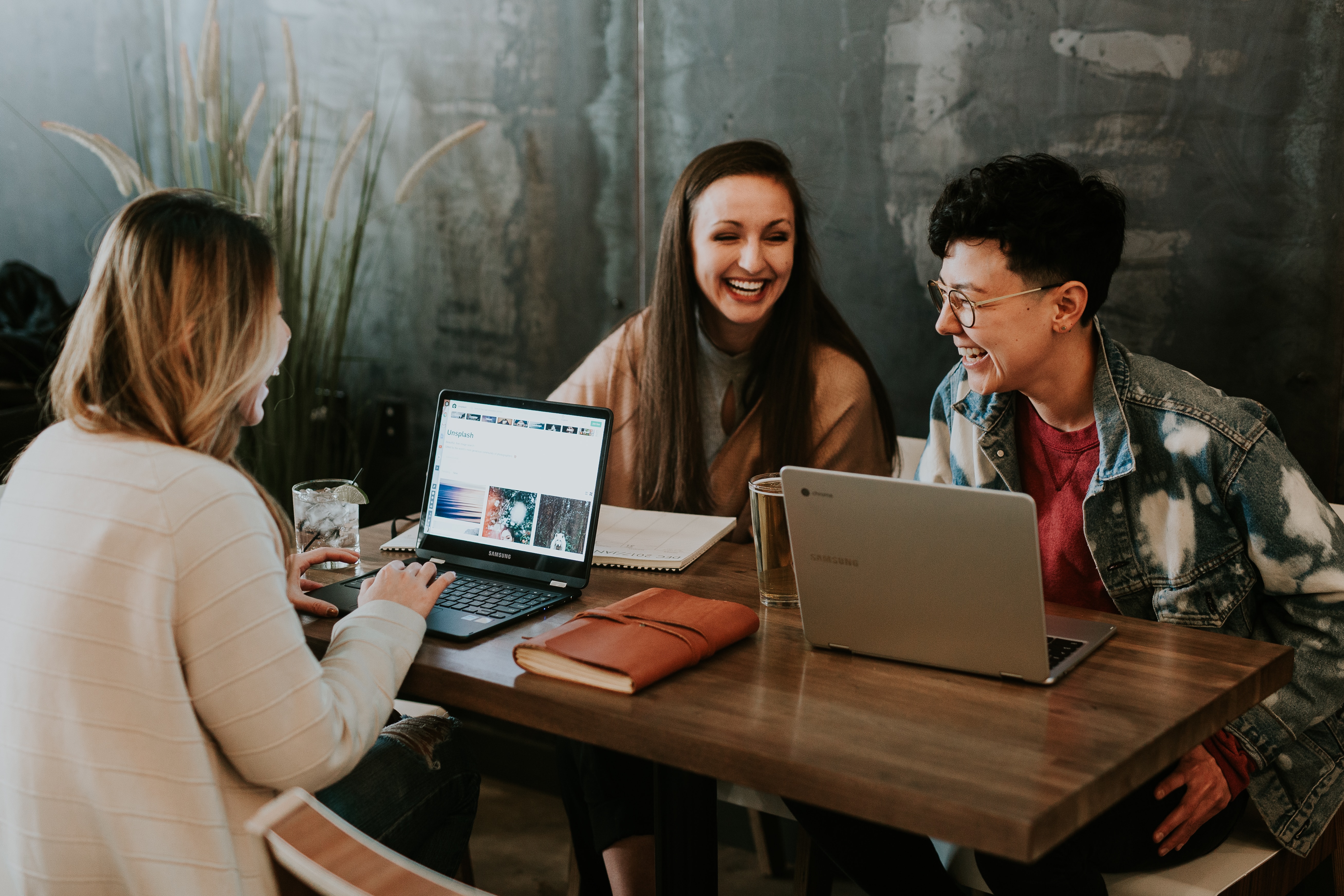 Group of people sitting on the table with laptops, discussing and smiling