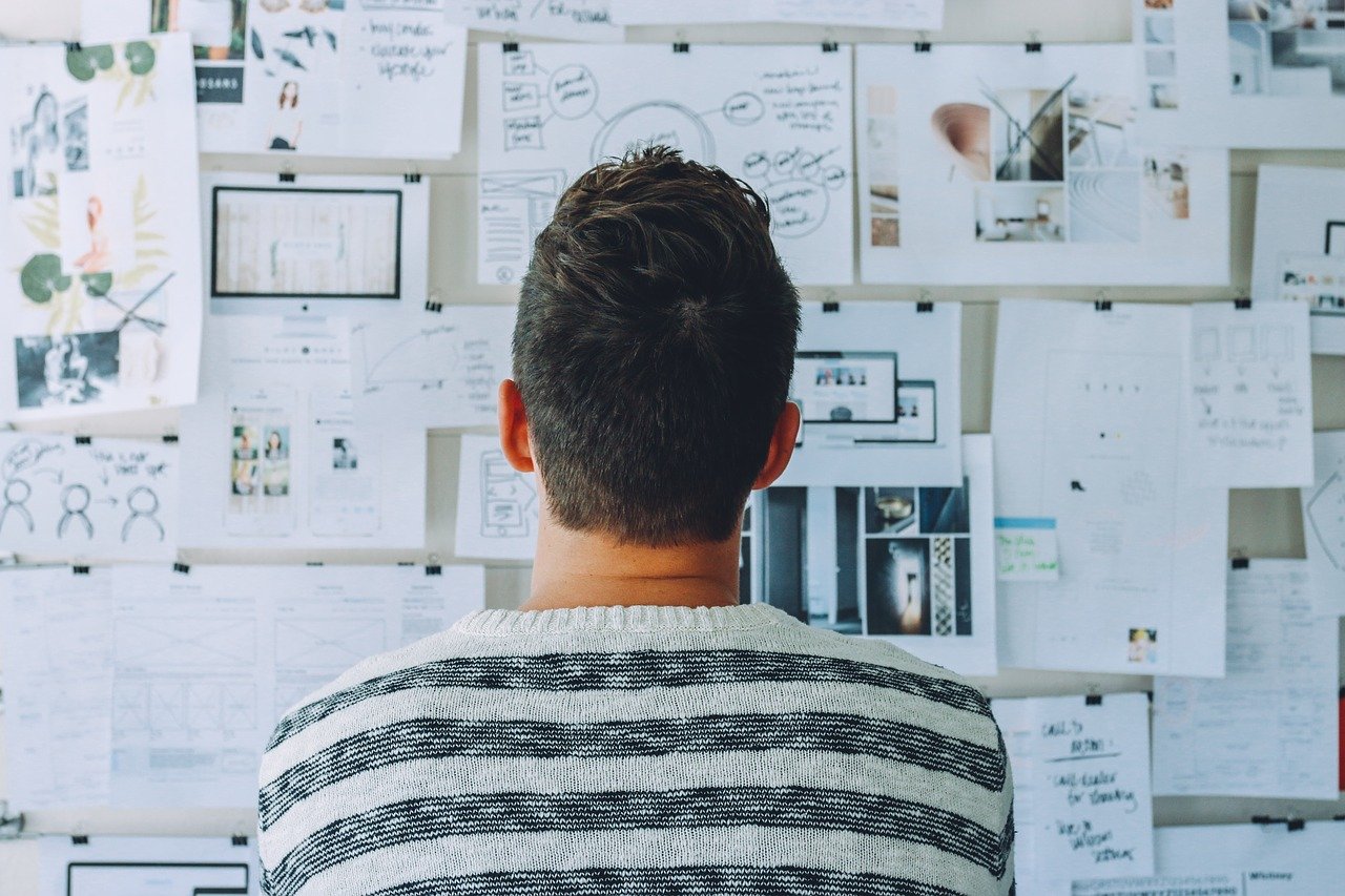 Man watching on the wall with a lot of posters and considering the best solution